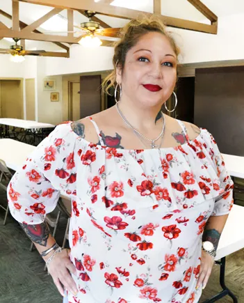 Una integrante de Divine Women sonriendo con una blusa de flores
