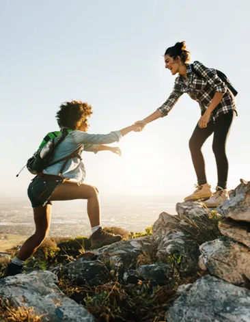 Dos mujeres de excursión; una ayuda a la otra a subir una roca